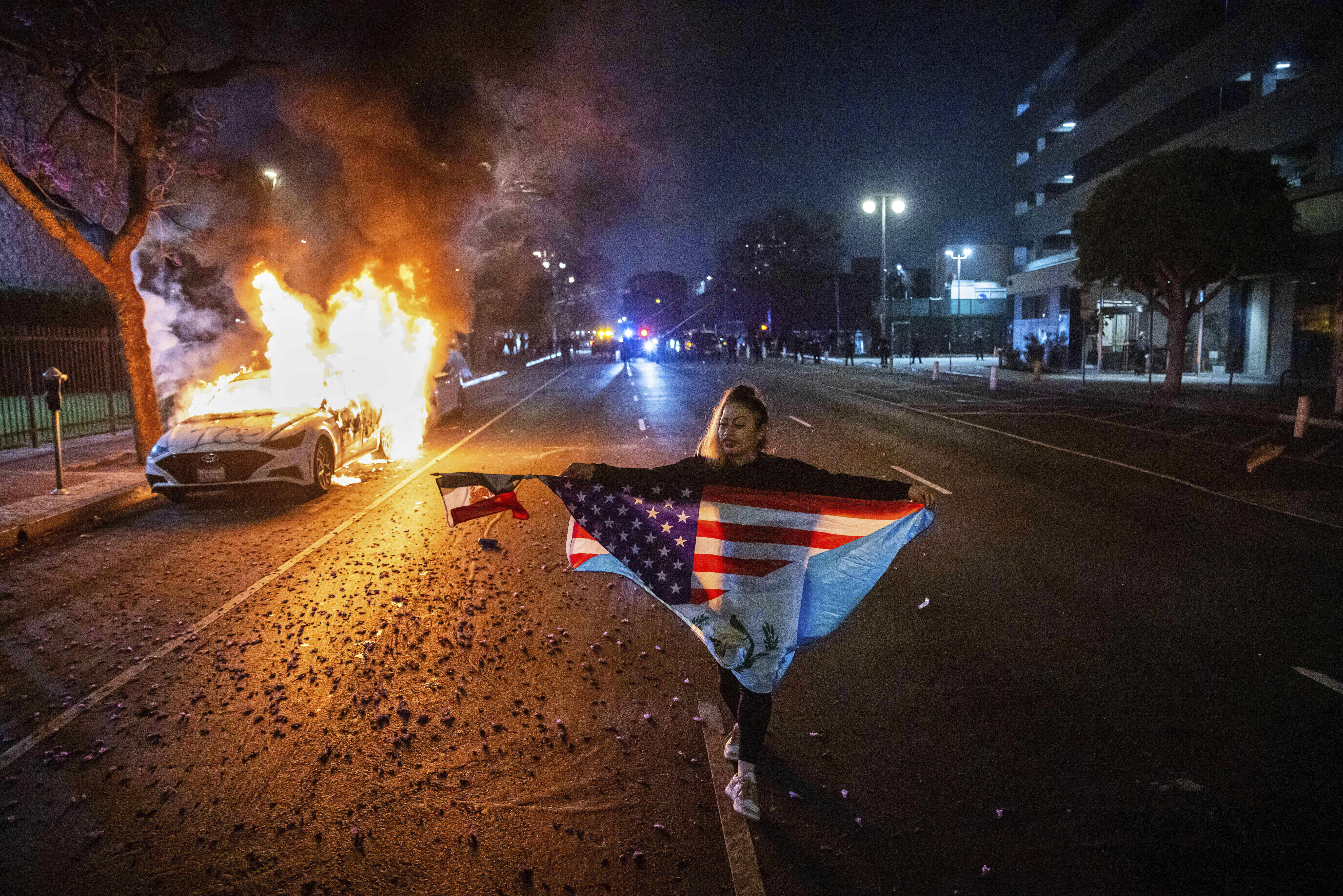 Eine Demonstrantin in Los Angeles posiert vor einem brennenden Auto. Die Proteste eskalierten, nachdem Donald Trump ankündigte, Militär in die Stadt zu schicken.