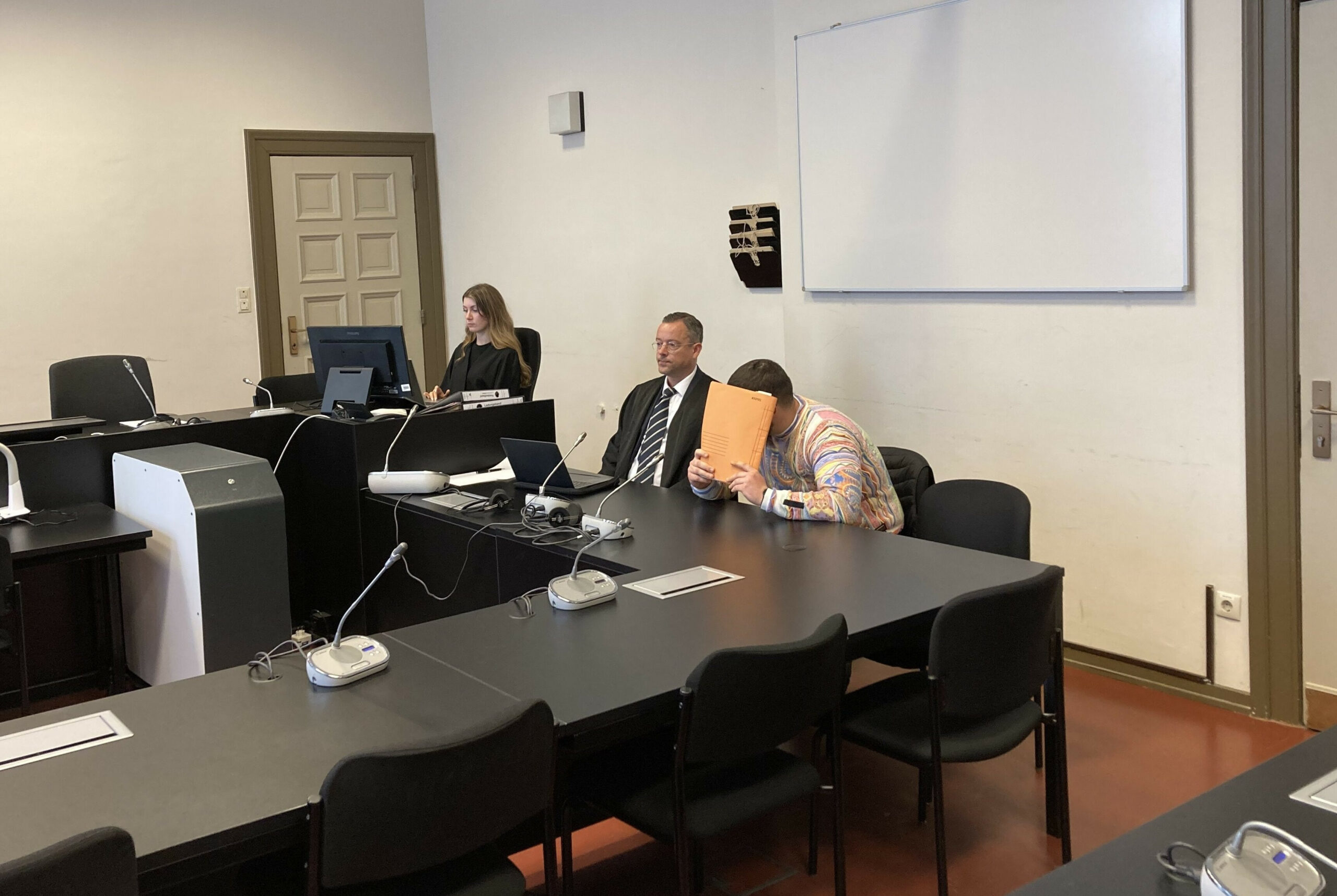 Der Angeklagte verbirgt sein Gesicht vor Gericht