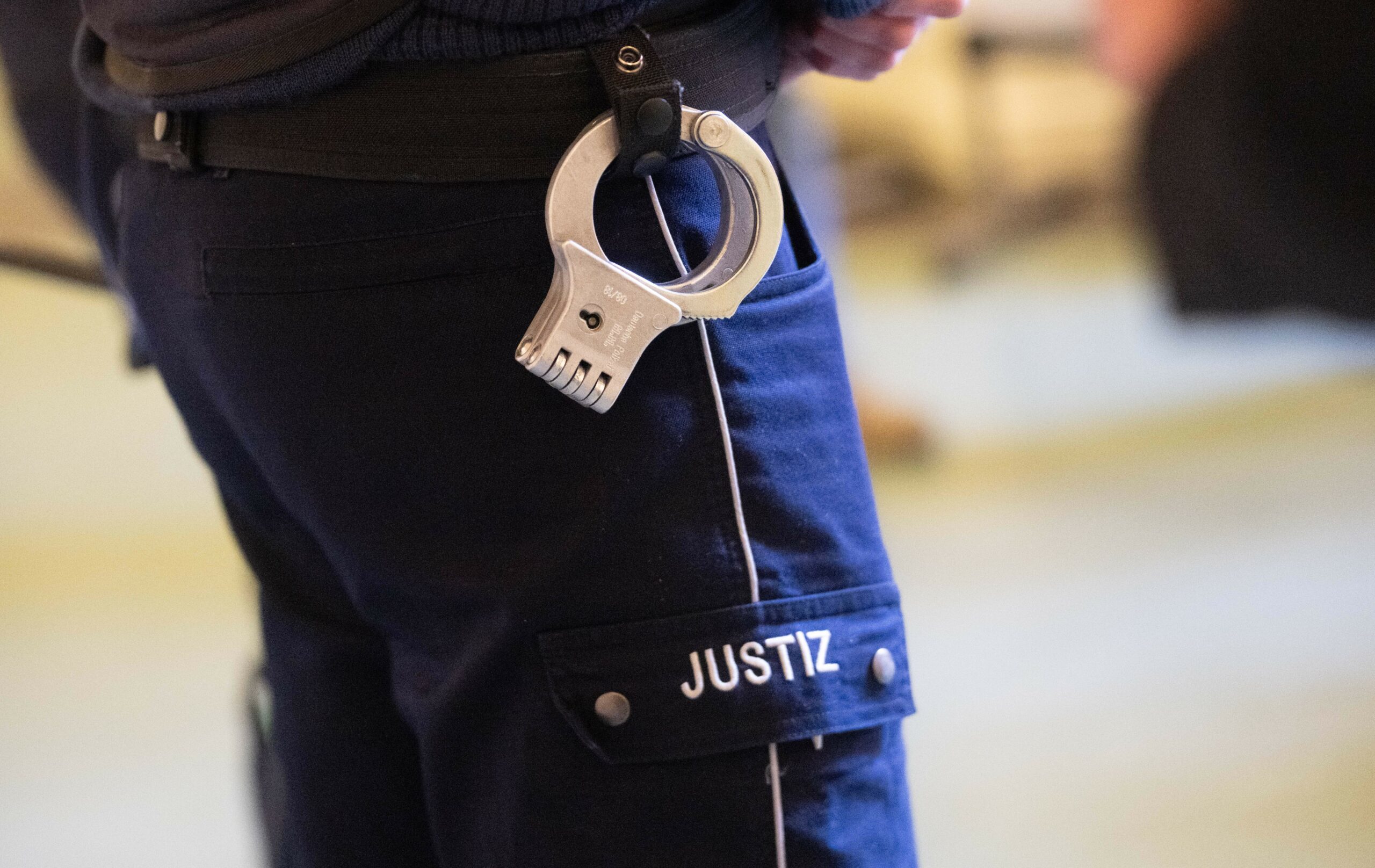 Justizbeamter mit Handschellen in einem Gerichtssaal (Symbolbild).