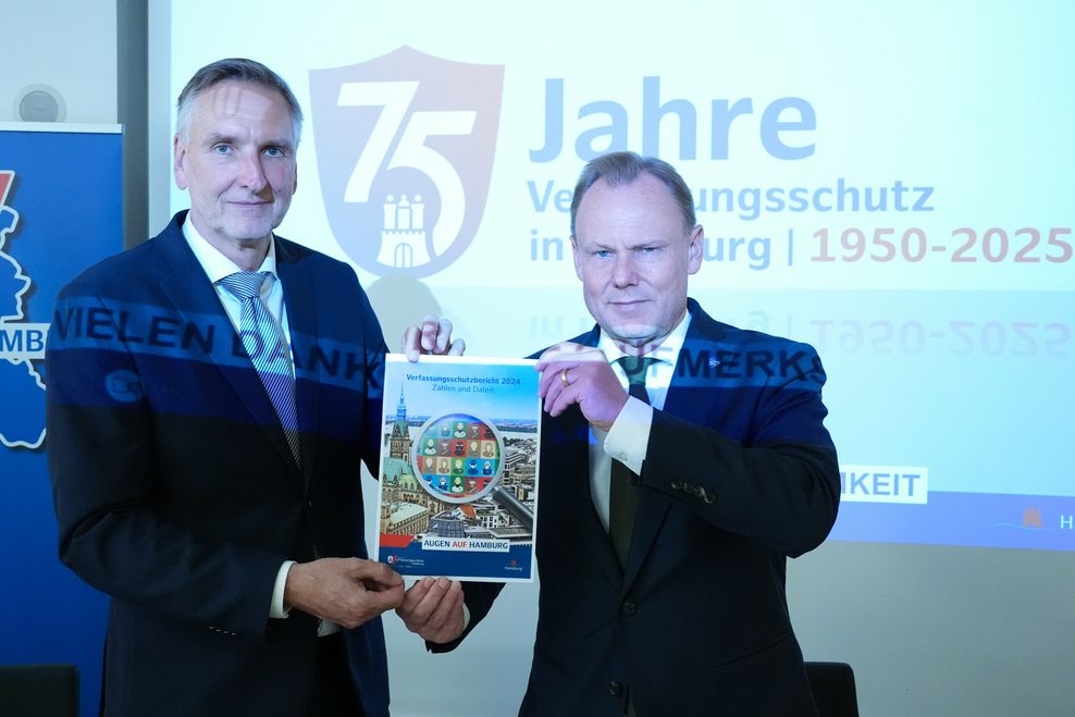 Torsten Voß (l), Leiter des Hamburger Landesamtes für Verfassungsschutz, und Andy Grote (SPD), Senator für Inneres und Sport, halten in der Innenbehörde der Vorstellung den Hamburger Verfassungsschutzbericht 2024 hoch.