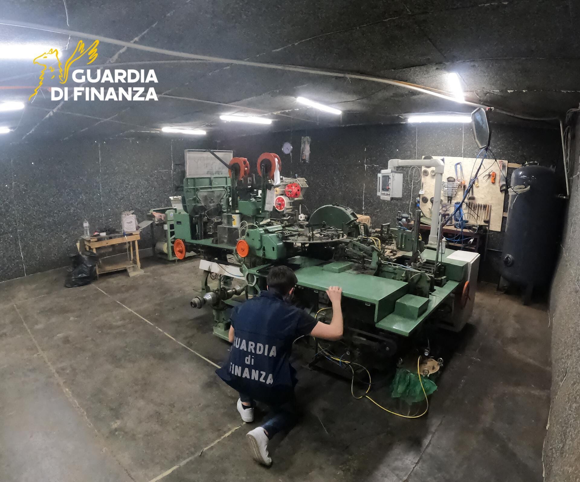 Ein Ermittler der Guardia di Finanza kniet im Industriegebiet der Stadt Piacenza in einer illegale Zigarettenfabrik