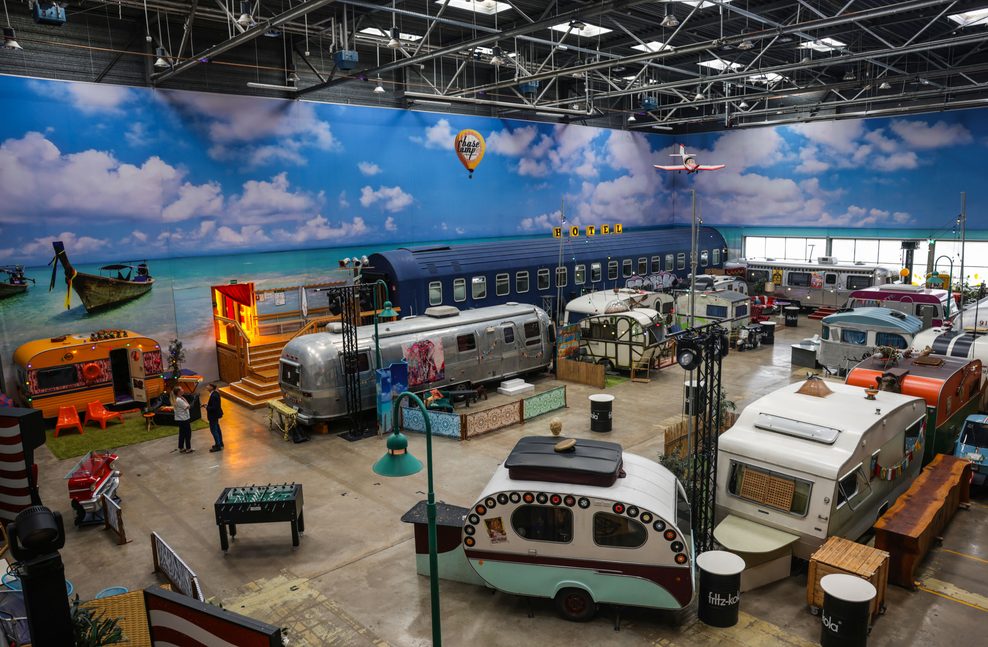 Mehrere Wohnwagen und Camping-Mobile stehen in der großen Halle, dem „Basecamp“.