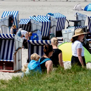Zahlreiche Urlauber sitzen bei sonnigem Wetter in den Strandkörben.