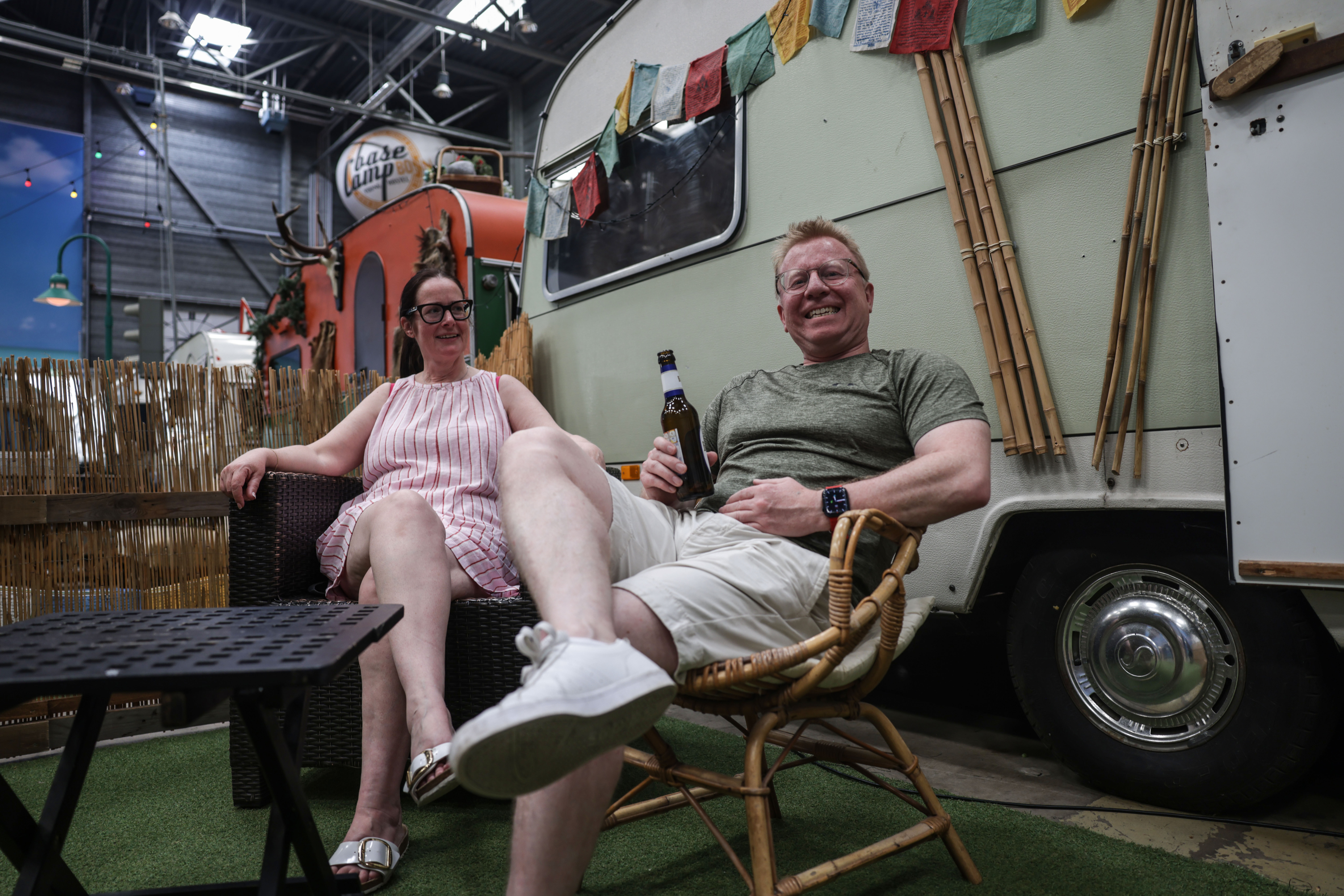 Simon Wombwell und Anne Taylor aus der Nähe von Bristol sitzen im Basecamp bei einem Wohnwagen – draußen ist es 30 Grad heiß.