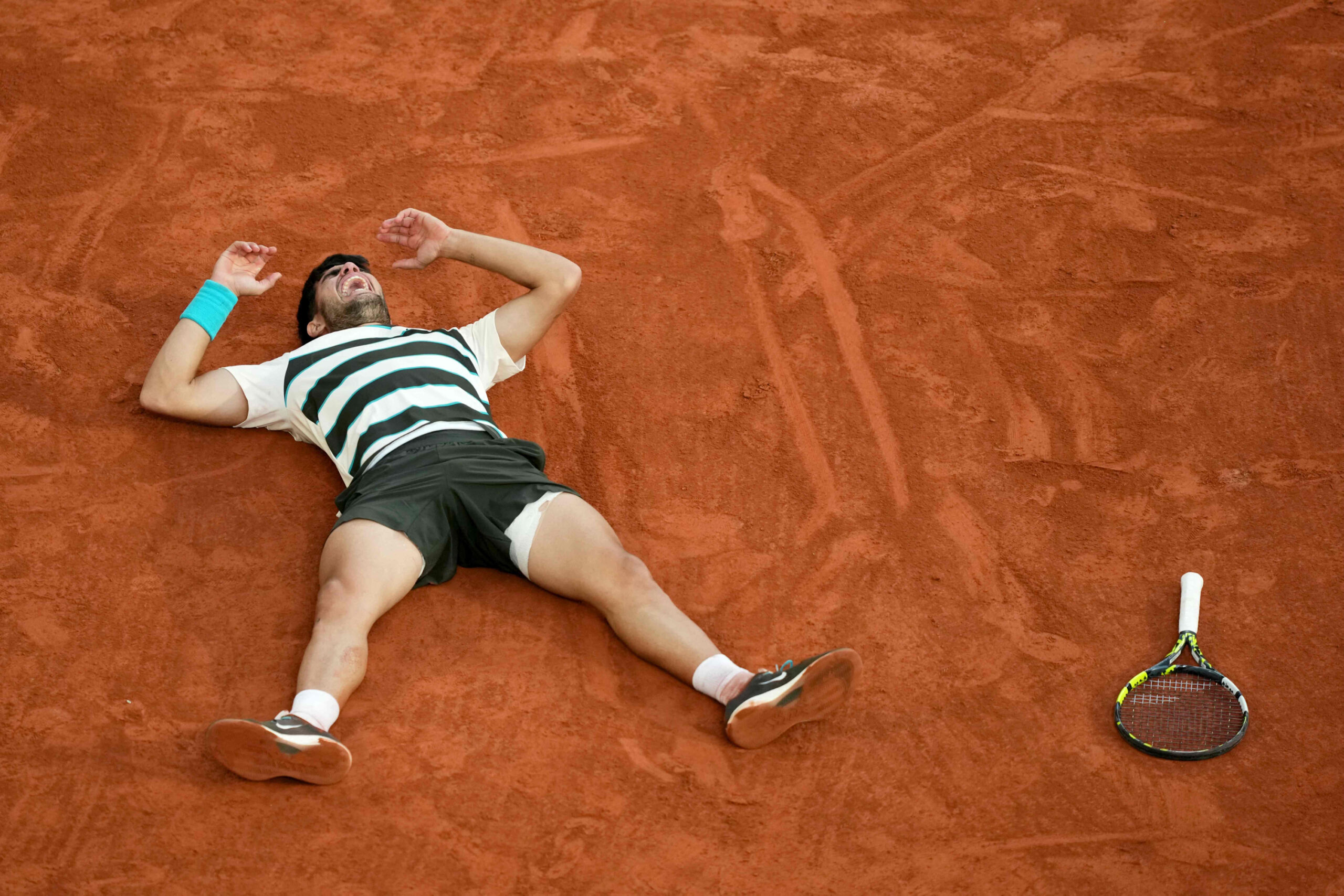 Carlos Alcaraz liegt nach dem verwandelten Matchball im Sand