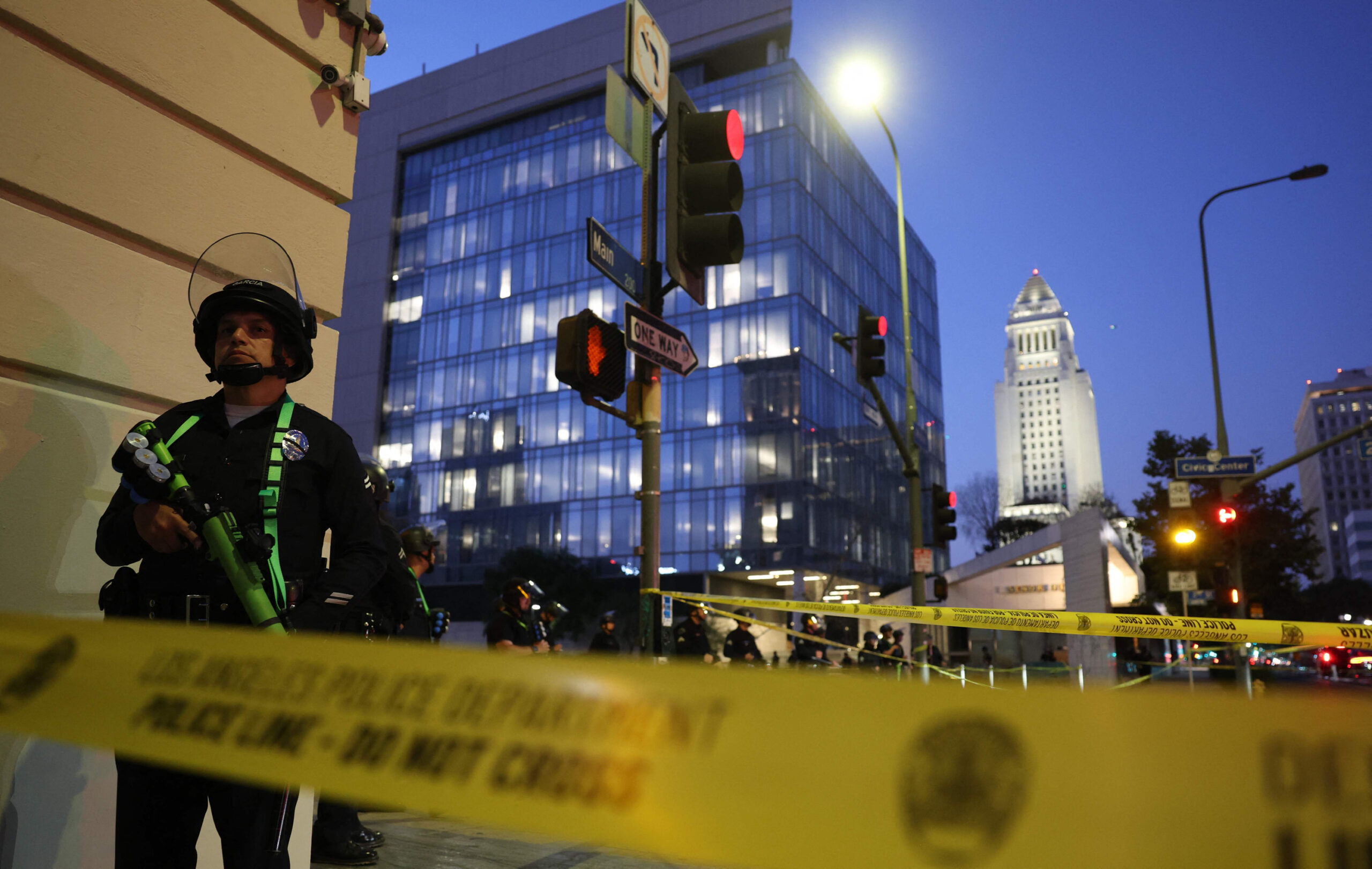 Ein Polizist steht in Los Angeles hinter einem Absperrband, um die Einhaltung der nächtlichen Ausgangssperre zu kontrollieren.