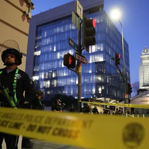 Ein Polizist steht in Los Angeles hinter einem Absperrband, um die Einhaltung der nächtlichen Ausgangssperre zu kontrollieren.