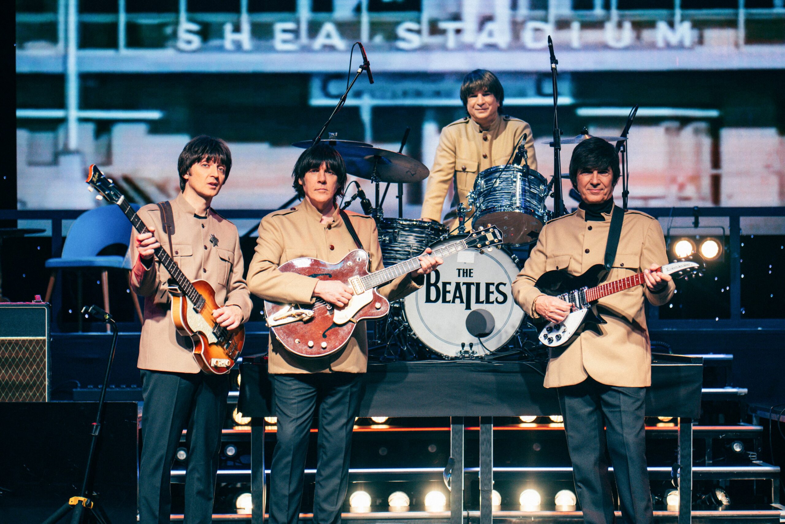 Vier Schauspieler stehen als The Beatles mit Instrumenten auf der Bühne.