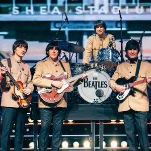 Vier Schauspieler stehen als The Beatles mit Instrumenten auf der Bühne.