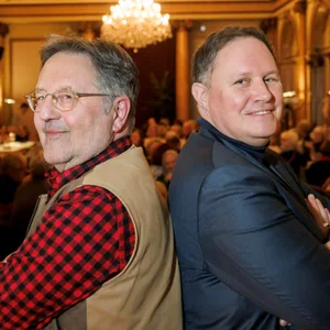 Links Moritz, rechts Brosda, sie stehen Rücken an Rücken und schauen in die Kamera. Im Hintergrund Publikum im Literaturhaus