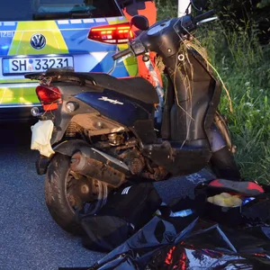 Der Roller des Verstorbenen steht vor einem Polizeiauto.