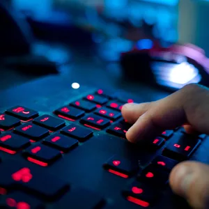 Ein Mann sitzt am Rechner und tippt auf einer Tastatur