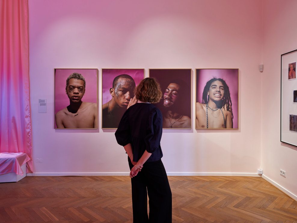 Eine Frau steht in einer Ausstellung vor einer Bilder-Serie.