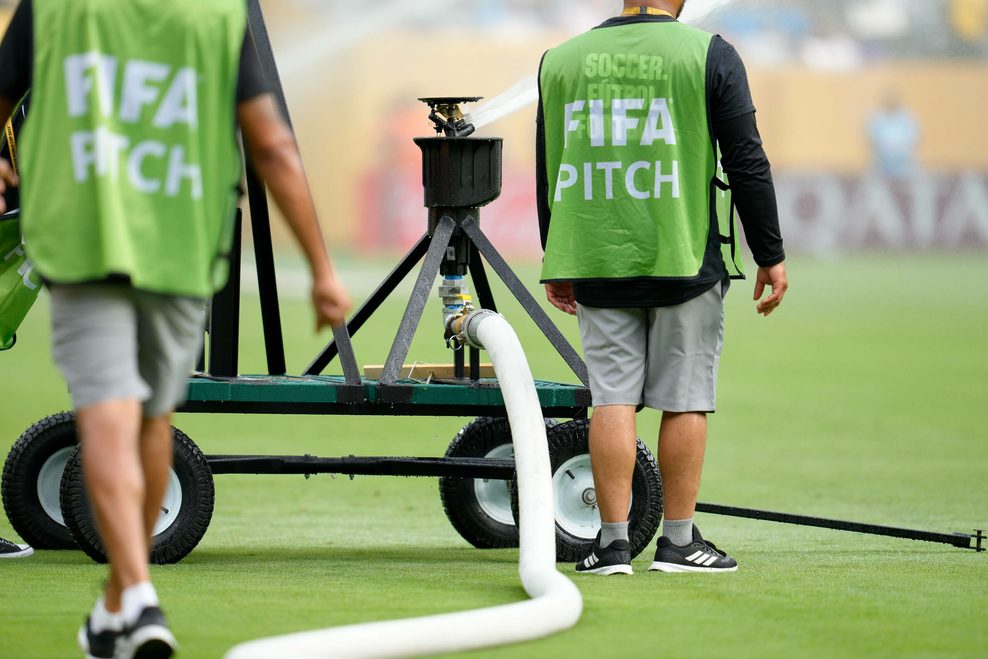 Platzwarte bewässern den provisorischen Rasen im MetLife Stadium mit großen tragbaren Sprinklern und Feuerwehrschläuchen.