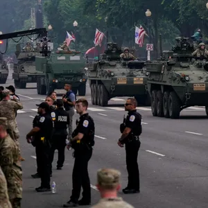 Soldaten fahren während einer Parade mit Panzern auf einer Straße.