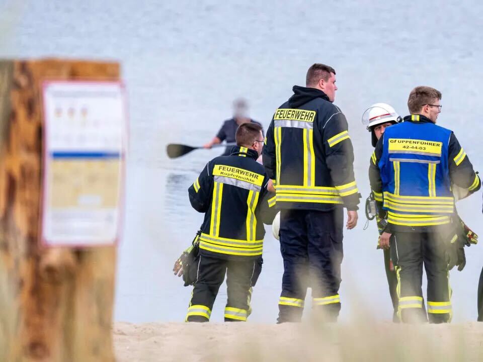 Feuerwehrkräfte stehen am Strand in Wassersleben.