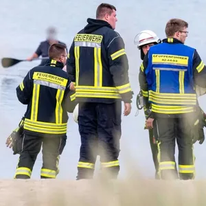 Feuerwehrkräfte stehen am Strand in Wassersleben.