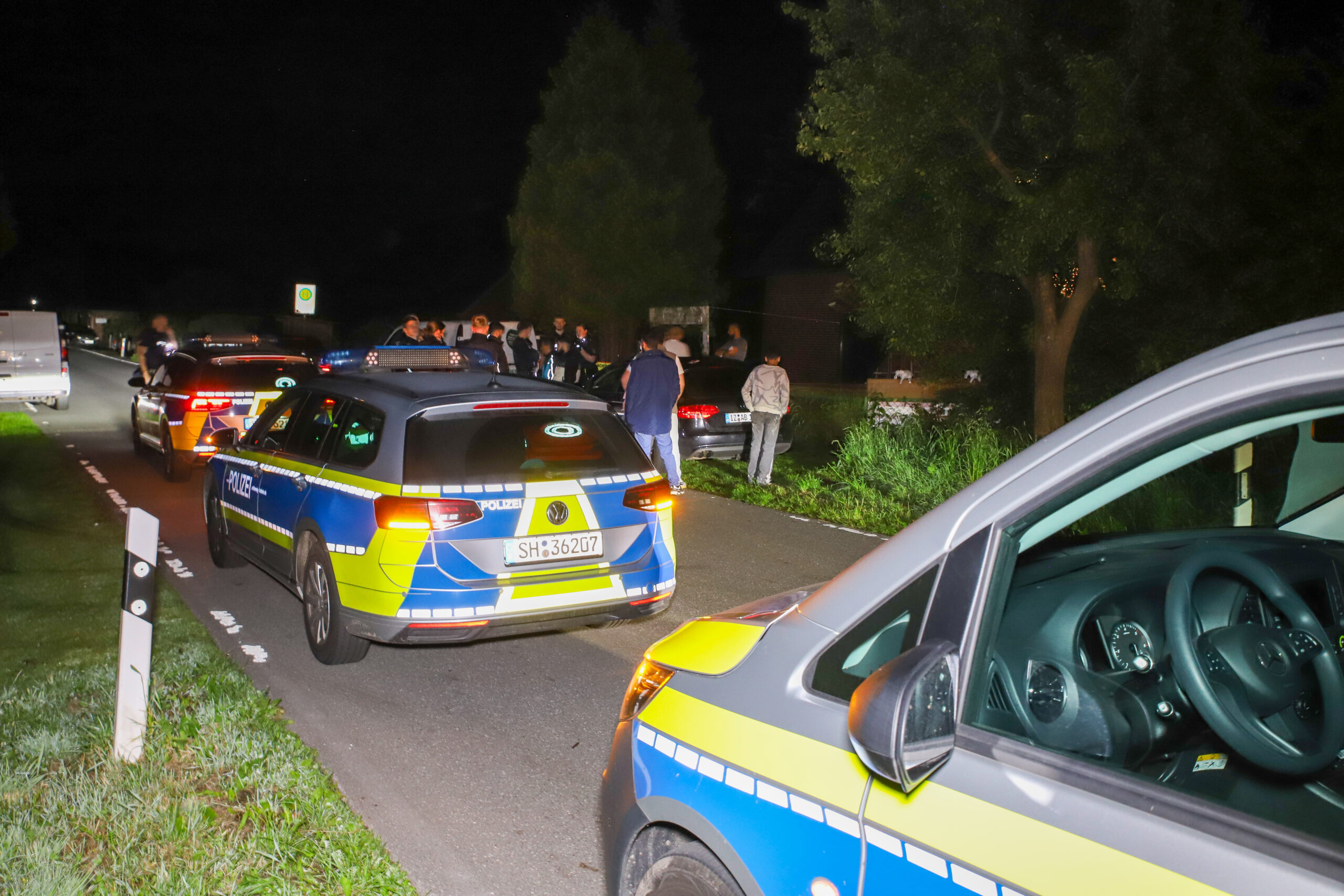 Polizisten stehen vor dem Mehrfamilienhaus in Neuenbrook
