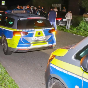 Polizisten stehen vor dem Mehrfamilienhaus in Neuenbrook