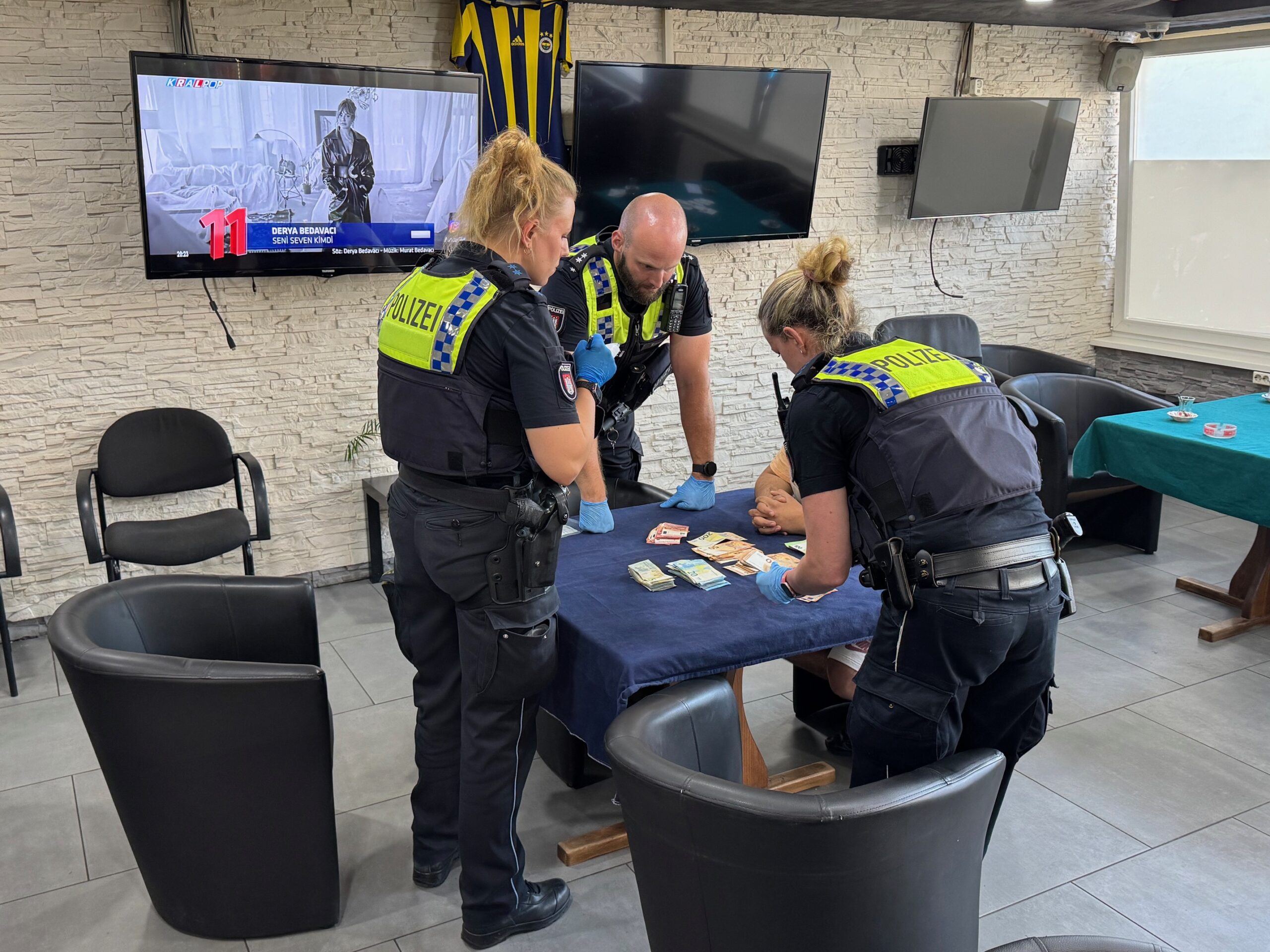 Einsatzkräfte der Polizei stehen vor einem Tisch mit Geldscheinen.