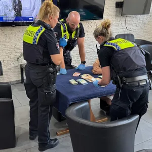 Einsatzkräfte der Polizei stehen vor einem Tisch mit Geldscheinen.
