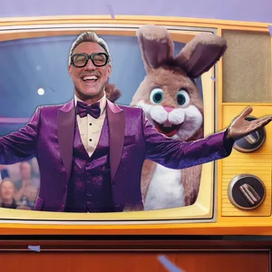 Ein Mann trägt eine Brille und einen violetten Anzug.