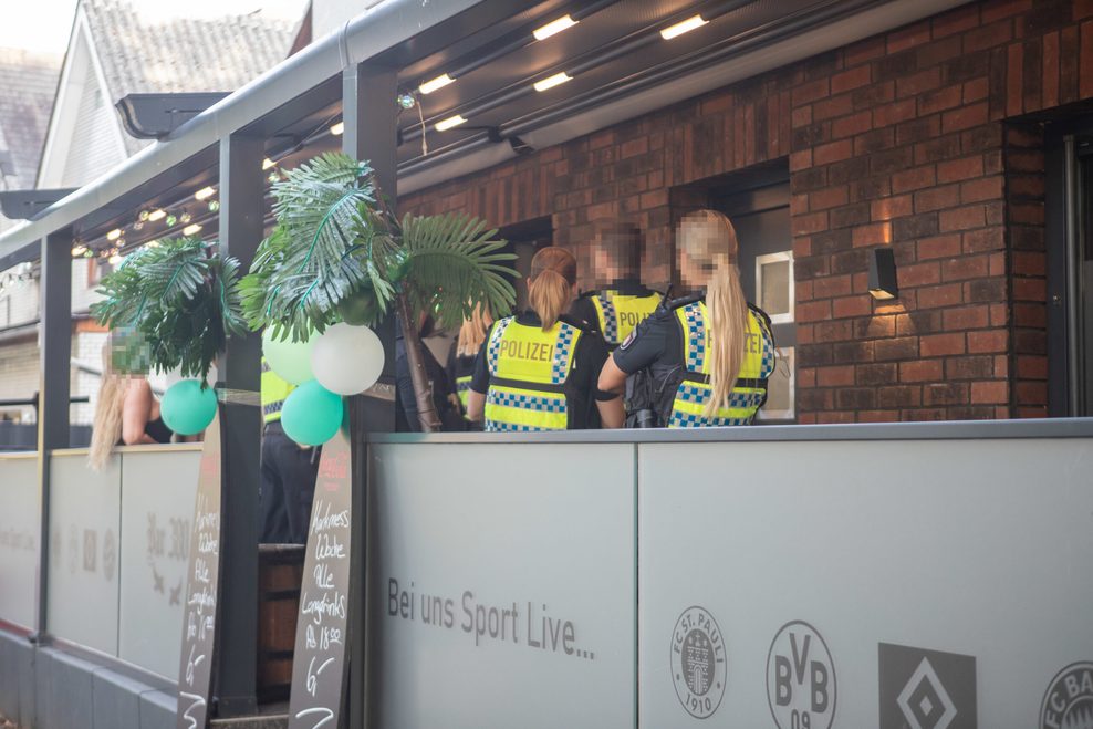 Polizisten stehen während einer Durchsuchung in einer Bar.