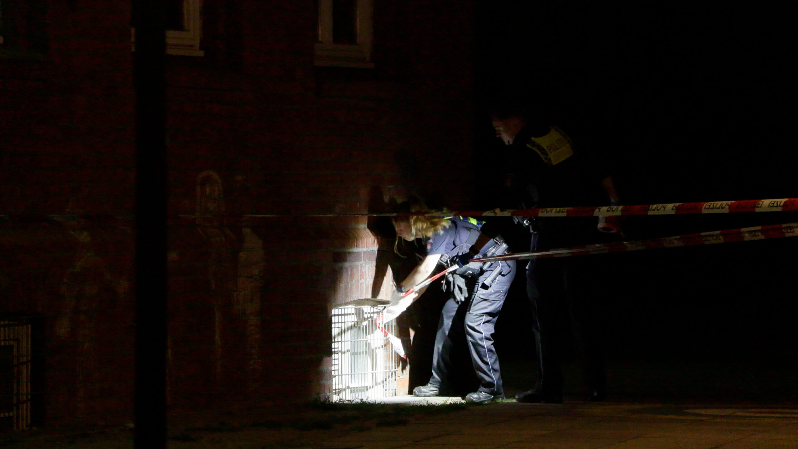 Eine Polizistin untersucht das Fenster, durch das die Täter in die Grundschule Finkenwerder eingedrungen sind.