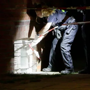 Eine Polizistin untersucht das Fenster, durch das die Täter in die Grundschule Finkenwerder eingedrungen sind.