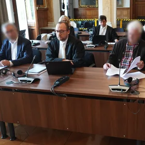 Die drei Angeklagten (vorn 2.v.l., vorn 2.v.r. sowie hinten r.) sitzen neben ihren Anwälten im Ziviljustizgebäude in Hamburg.