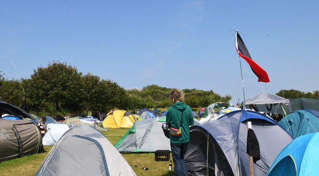 Zelte und eine schwarz-rote Flagge einer Antifagruppe im Punk-Protestcamp auf der Festwiese.