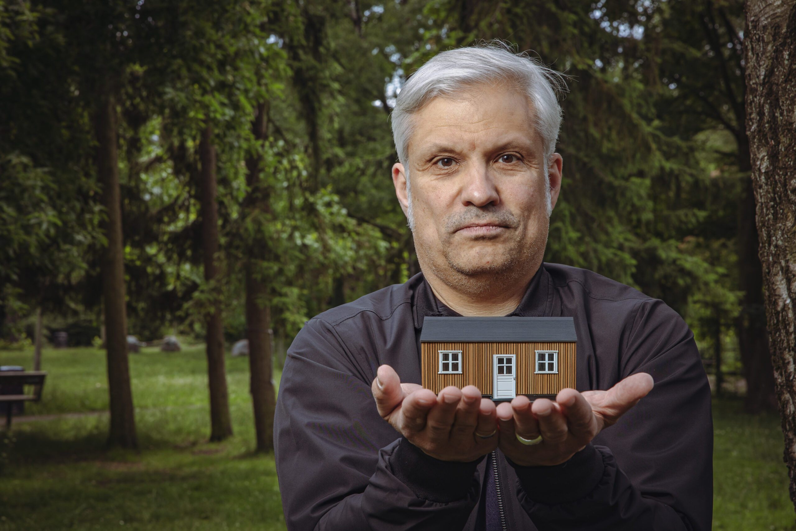 Ein Mann mit einem kleinen Haus in der Hand