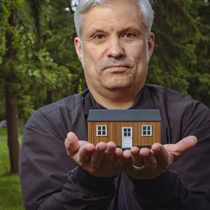 Ein Mann mit einem kleinen Haus in der Hand