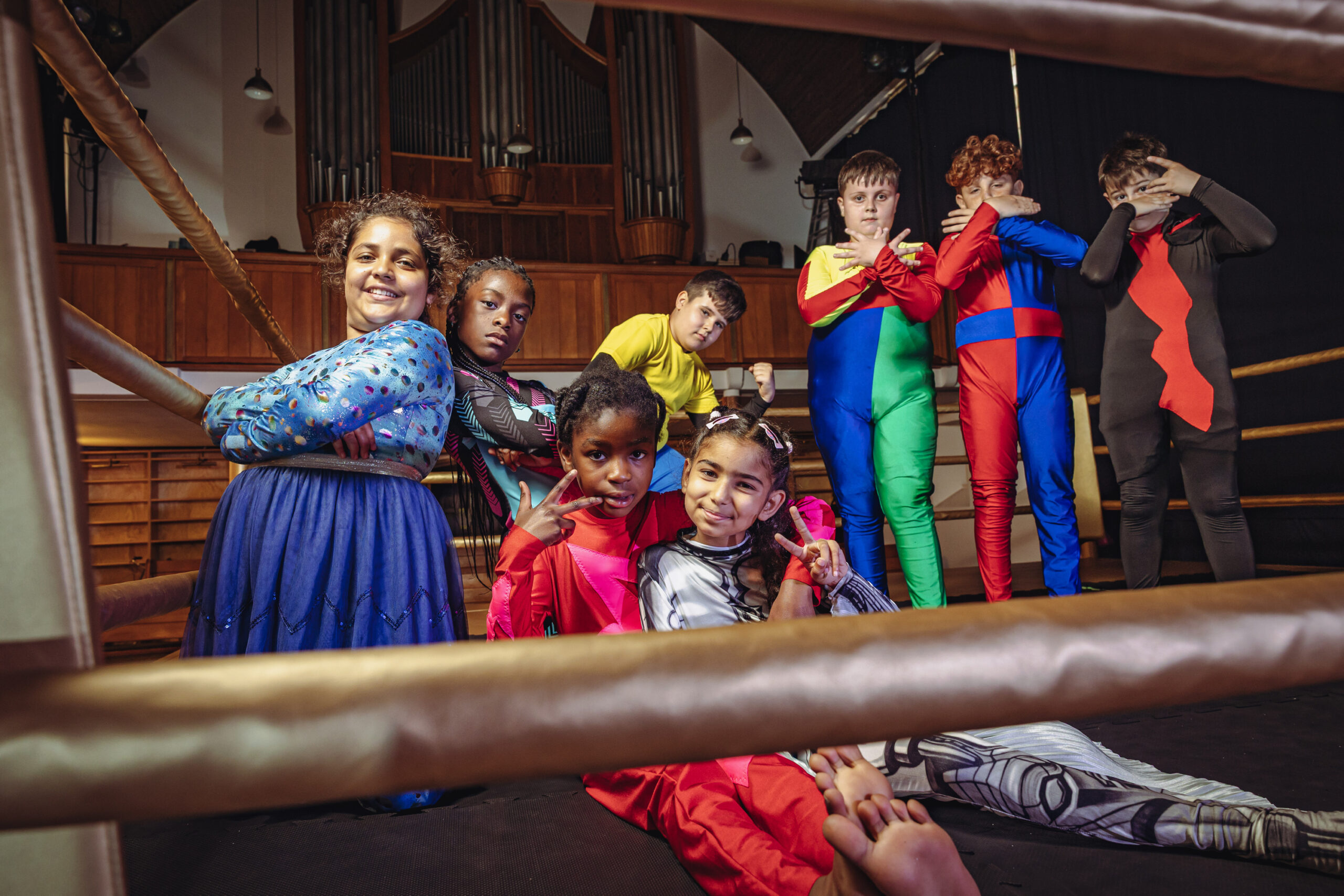 Acht Kinder der Aufführung „Super Wrestling“ stehen und sitzen im Ring.
