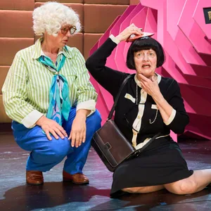 Drei Schauspieler sitzen mit geschockten Gesichtsausdrücken auf der Bühne.