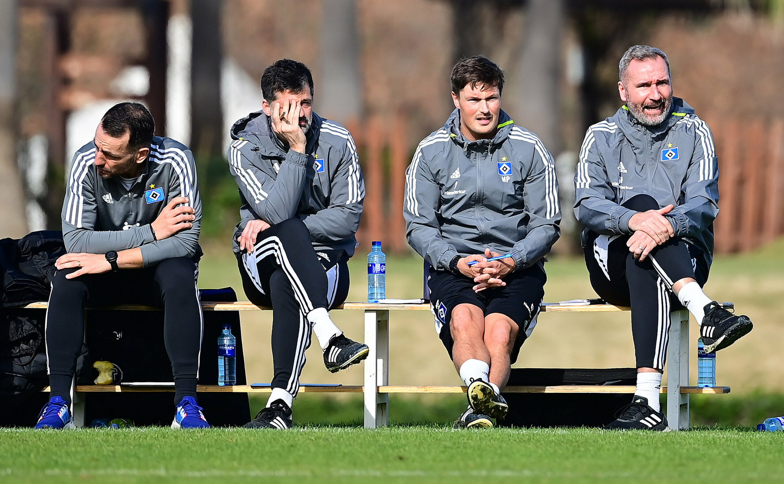 Sven Höh, Filip Tapalovic, Merlin Polzin und Tim Walter sitzen auf einer Trainerbank nebeneinander