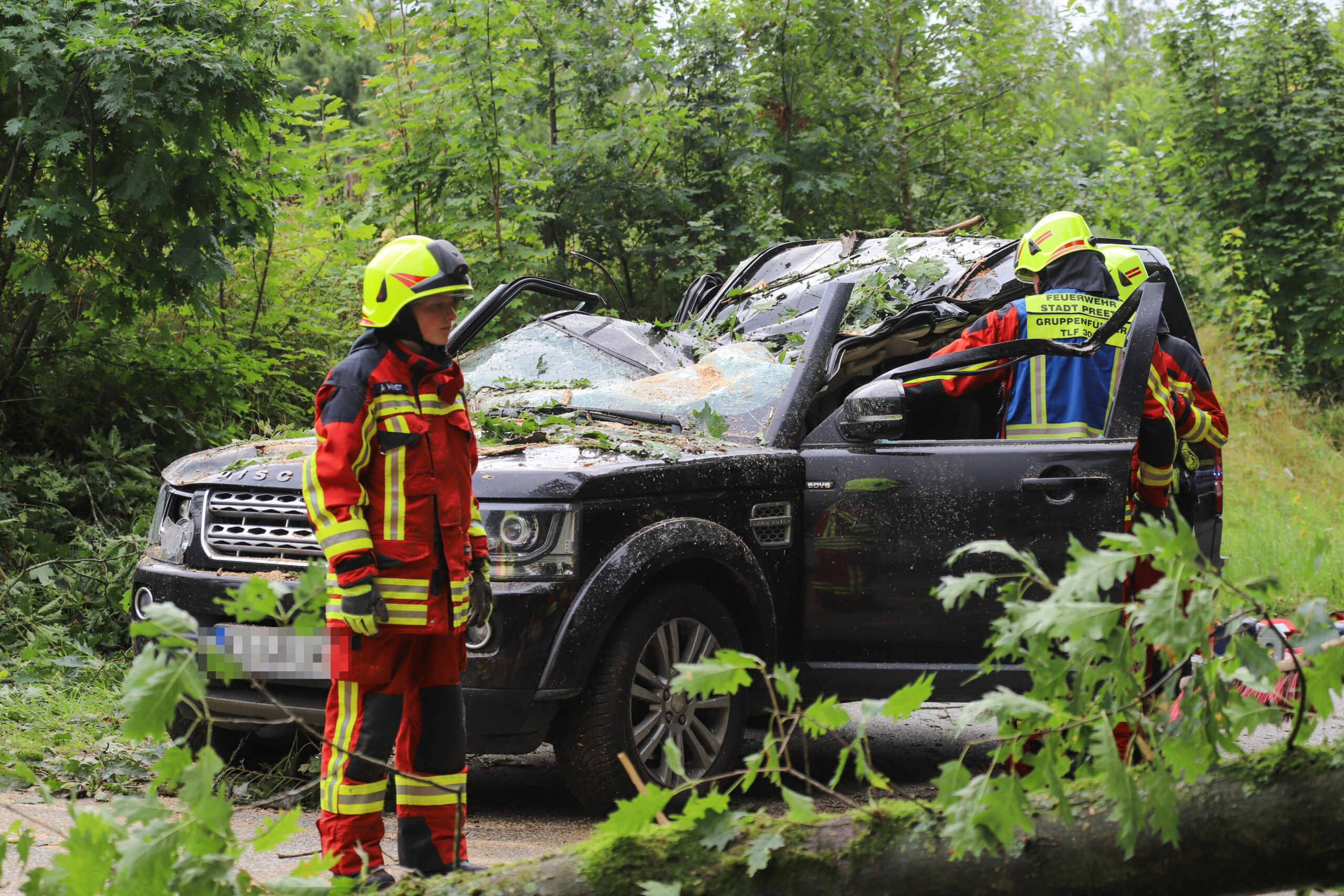 Feuerwehrkräfte stehen an dem verunfallten Auto.