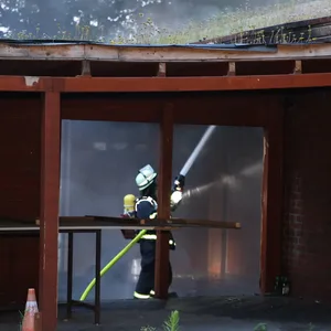 Ein Retter bekämpft die Flammen mit Wasser.