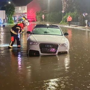 Ein Feuerwehrmann kontrolliert ein Fahrzeug, dessen Insassen durch den Starkregen in Not geraten sind.