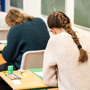 Schüler:innen sitzen in einem Klassenzimmer und schreiben das Biologie-Abitur.