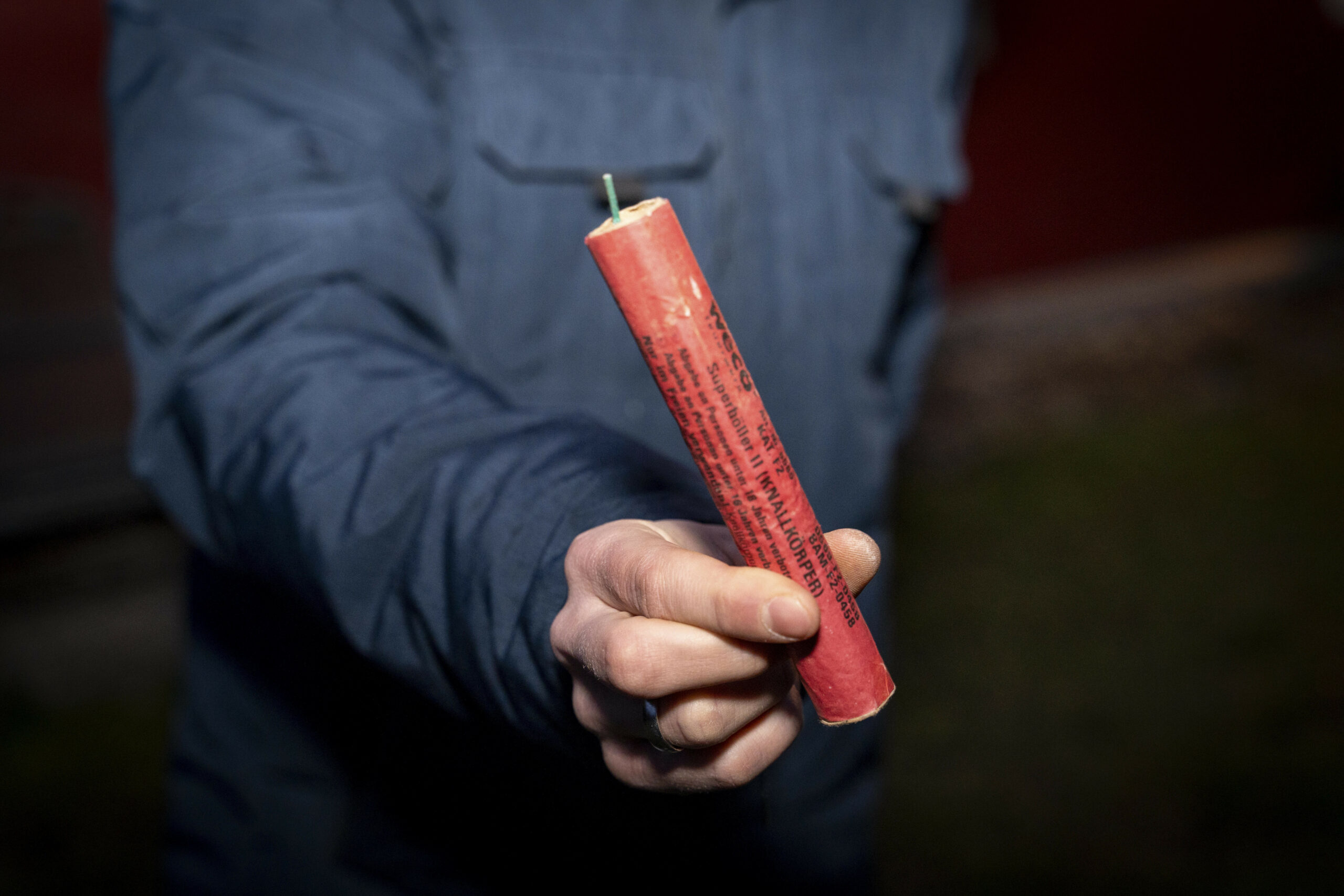 Mann hält an Silvester einen großen Böller im Freien in der Hand
