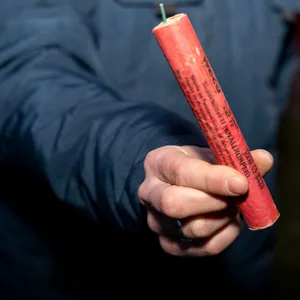 Mann hält an Silvester einen großen Böller im Freien in der Hand