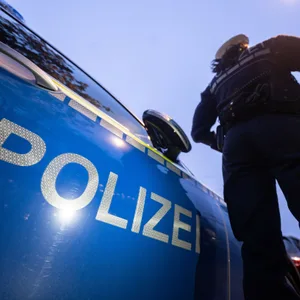 Eine Polizistin steht neben einem Polizeifahrzeug. (Symbolbild)