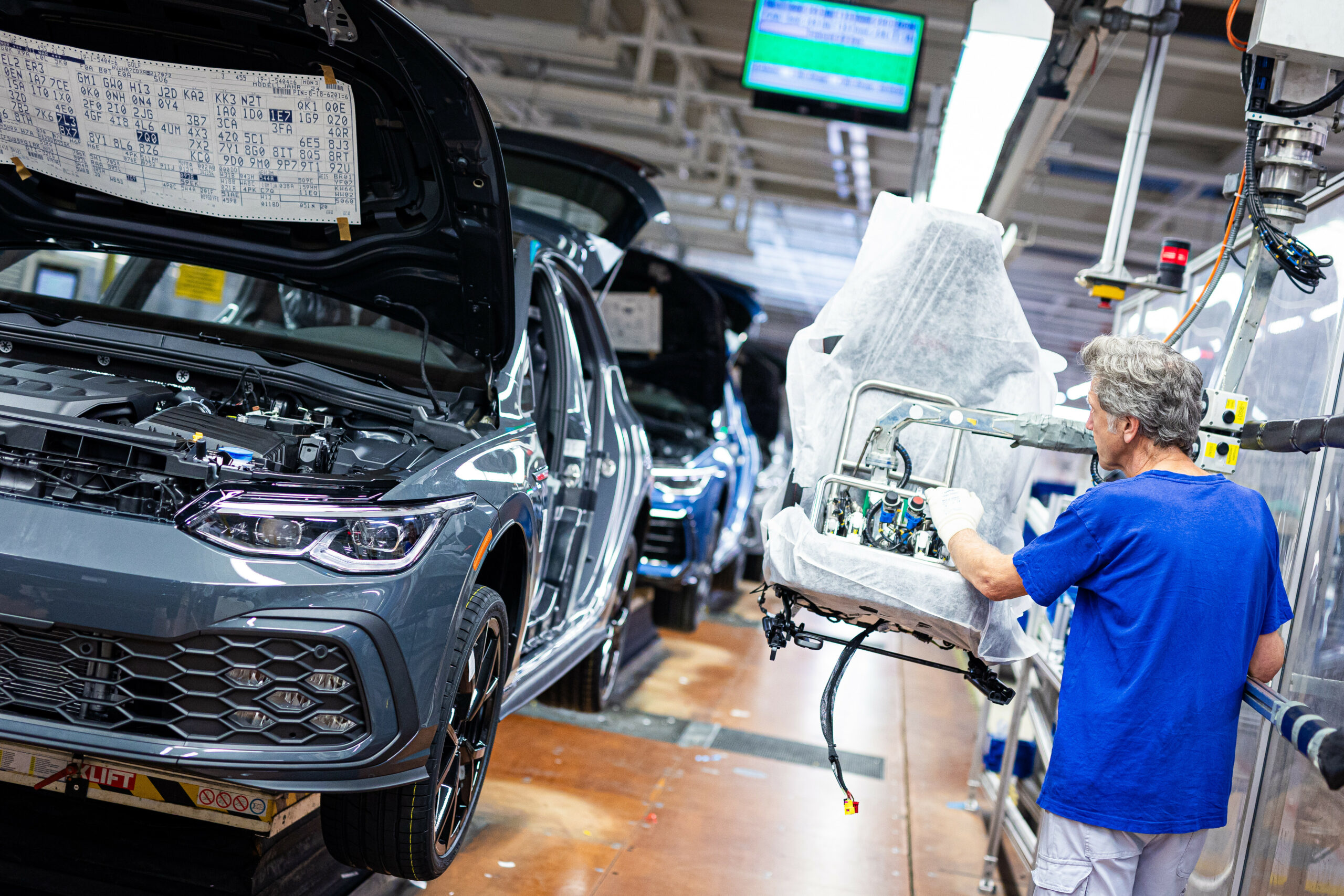 Ein Mitarbeiter montiert in einem Fahrzeug im VW Werk einen Autositz.