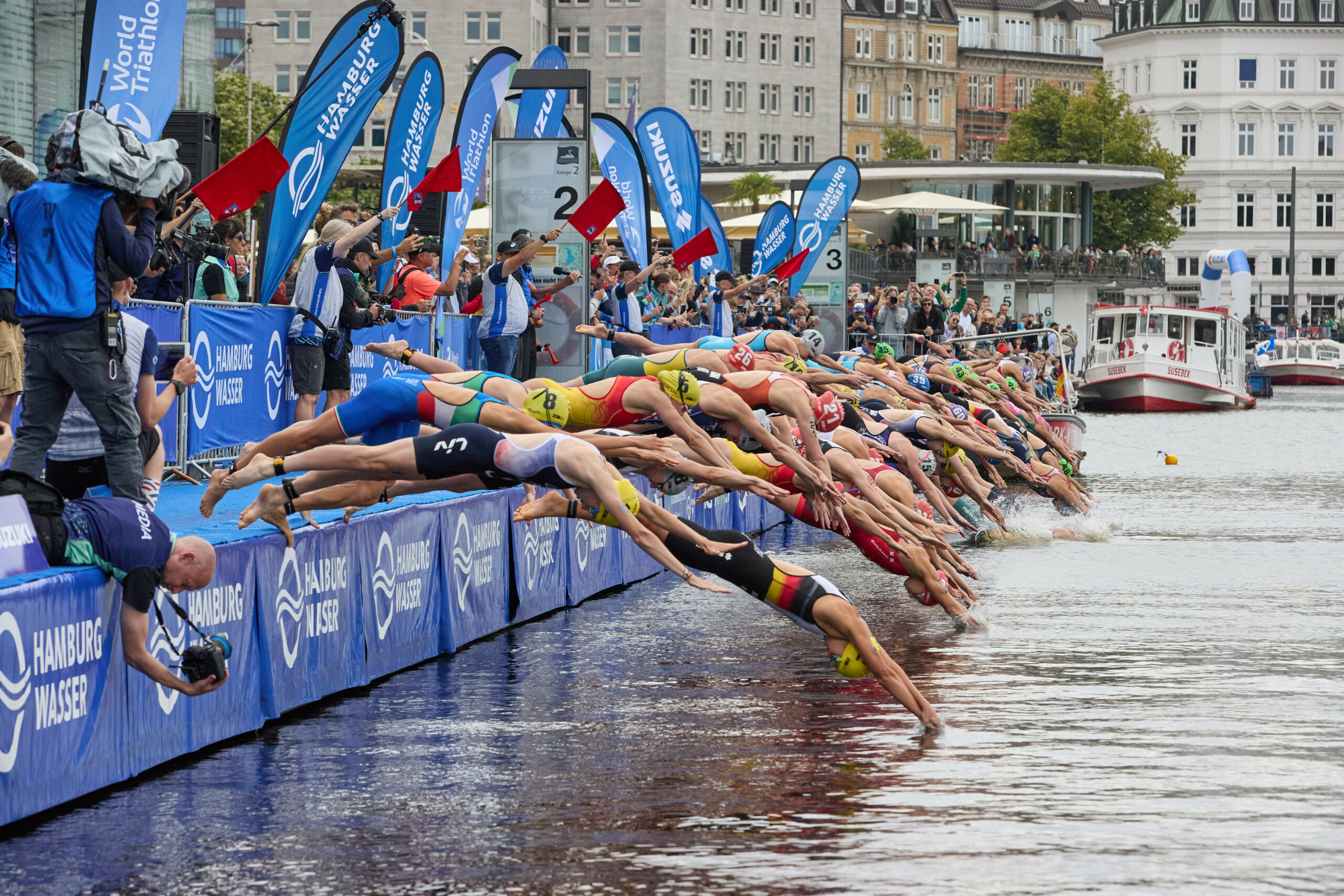 Menschen springen beim Triathlon in die Alster
