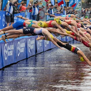 Menschen springen beim Triathlon in die Alster