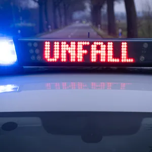 Ein Polizeiauto steht mit Blaulicht auf einer Landstraße.
