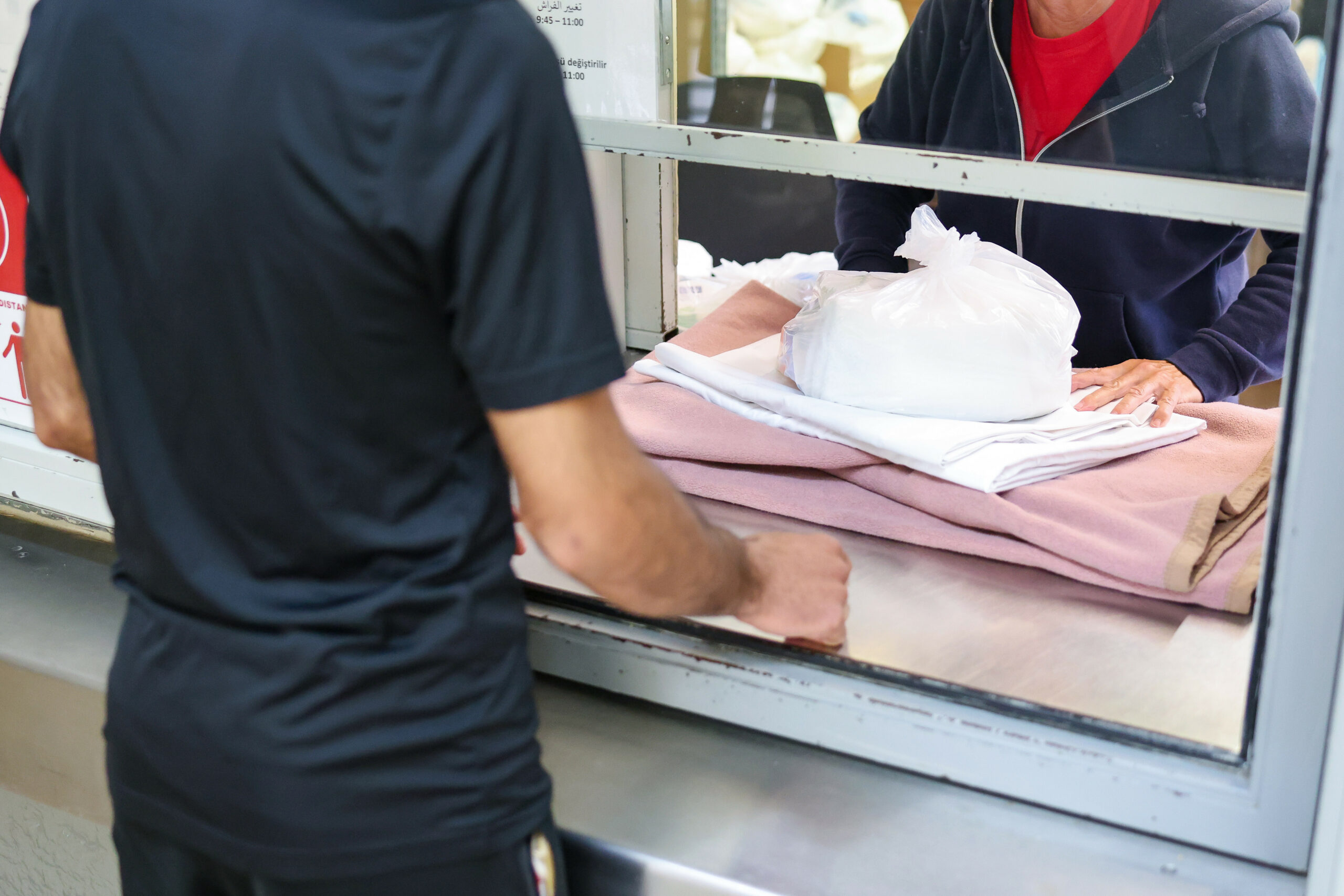 Ein Migrant bekommt in einer Zentralen Aufnahmeeinrichtung für Asylbewerber die Erstausstattung an Besteck, Bettwäche und Hygieneartikeln überreicht. (Symbolbild)