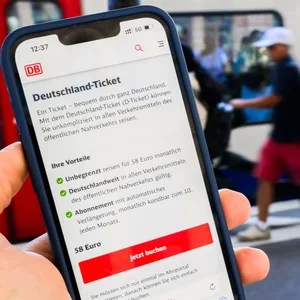 Eine Information zum Kauf des Deutschlandtickets ist auf dem Display eines Smartphones am Hauptbahnhof Hannover zu sehen.