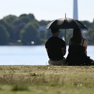 Menschen mit Sonnenschirm an der Alster
